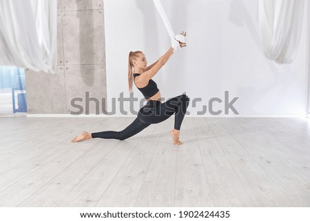 beautiful caucasian slim woman is doing stretching training in light modern studio
