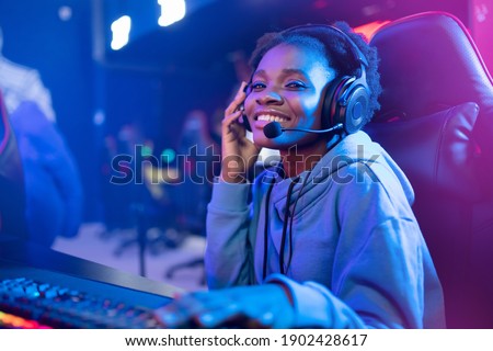 Young african happy woman professional gamer win in online video game with headphones, neon background.