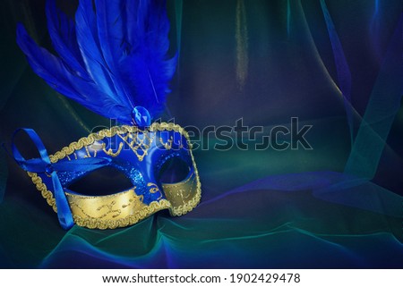 Photo of elegant and delicate Venetian mask over blue dark chiffon background