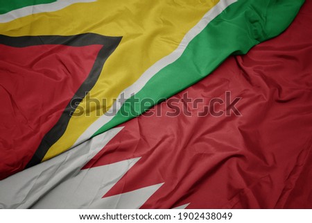 waving colorful flag of bahrain and national flag of guyana. macro