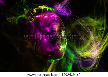 Portrait of young woman amid light painting , Over Black Background. Long exposure photo, light drawing at long exposure
