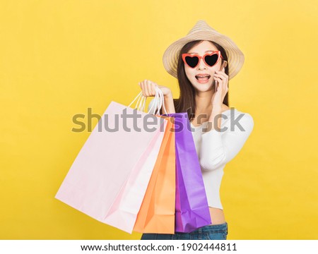 happy young woman holding shopping bags and talking on mobile phone