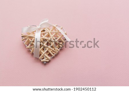 Wooden heart, woven. Pink background.