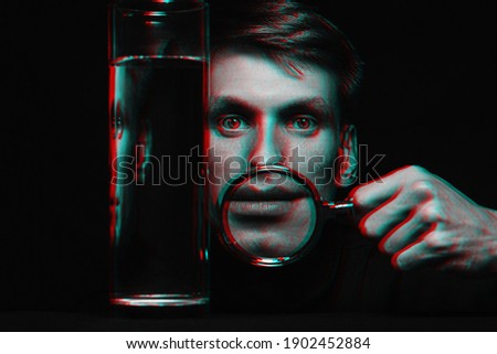 abstract portrait of a man through a magnifying glass and a glass of water. Black and white with 3D glitch virtual reality effect