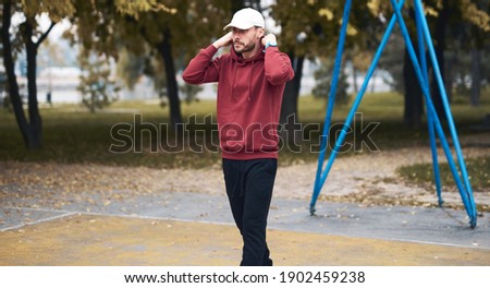 Athletic sporty man training in hoodie sweatshirt in urban city park basketball court.