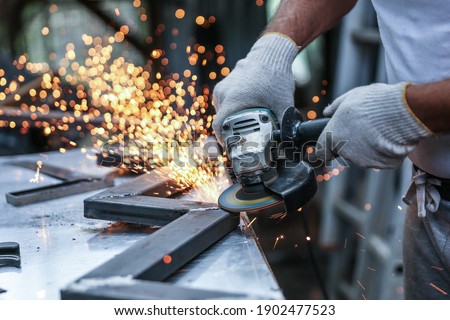 the hands of the master saw the metal with a grinder. metal works in the workshop close up Royalty-Free Stock Photo #1902477523