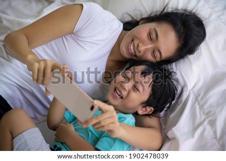mother and her son Taking pictures or selfie or video call or relatives in a bed. Concept of new generation, family, parenthood, authenticity, connection