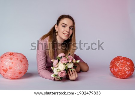 be touched with flowers by a girl on a pink background in a pink polka dot dress.	
