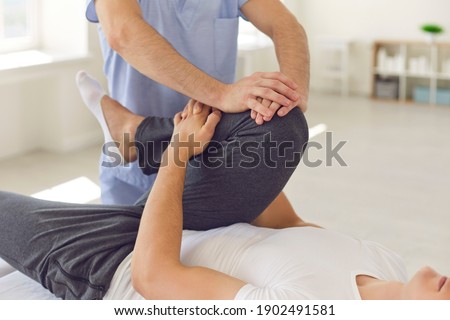 Cropped image of a physiotherapist massaging and kneading a patient's leg provides medical care for sprained ligaments. Concept of rehabilitation and recovery after physical leg injuries. Royalty-Free Stock Photo #1902491581