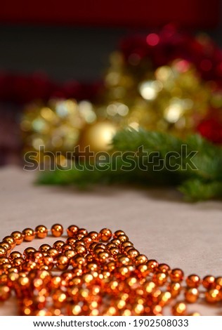 Background on craft paper are orange beads, gold and red tinsel, green spruce branches. Decor, decoration for the New Year and Christmas, empty space for text, congratulations, product advertising.