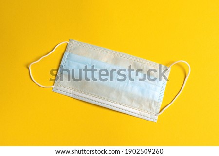 Surgical three-layer mask with rubber ear straps to protect against bacteria. Disposable medical mask covering mouth and nose.