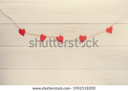 red hearts on a string on a white wooden background