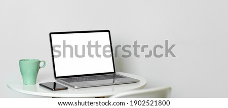 Cropped shot of portable workspace with laptop, smartphone, cup on coffee table, clipping path