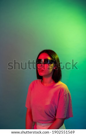 Young asian woman wearing smart glasses on colorful background videogaming or enjoying augmented reality