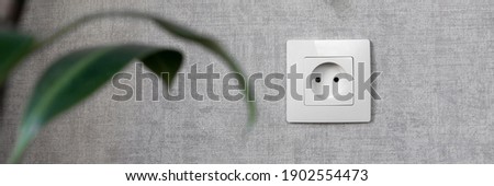 Electrical outlet on the gray wall. Electricity, safety, energy saving concept. Banner.