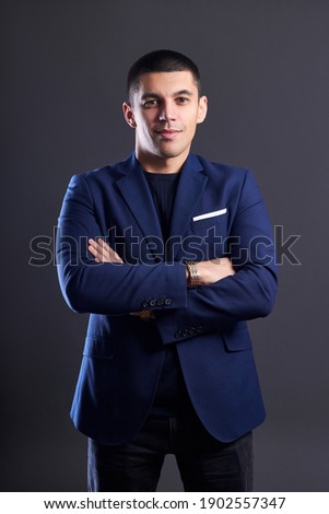 Portrait of a businessman in blue jacket on dark background in studio. Man with short haircut. Young confident manager smiles