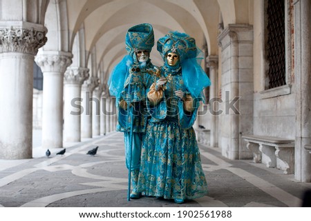 Masked couple in ornate costume at the the Venetian masquerade stands near St. Mark's Square in Venice