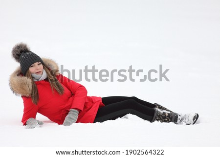 young woman in a red jacket in winter on a background of snow