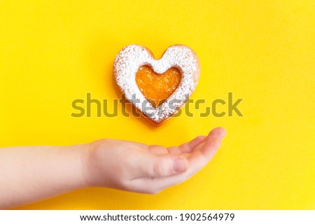 Take care and charity concept. Heart shaped cookie under child hand