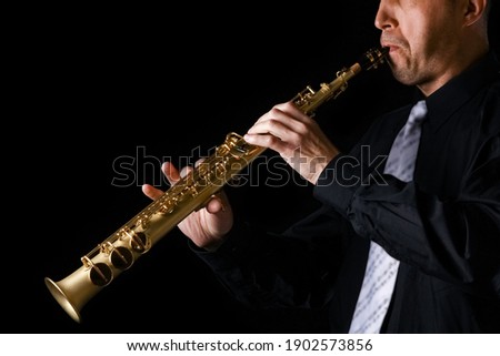 soprano saxophone in the hands of a guy on a black background Royalty-Free Stock Photo #1902573856
