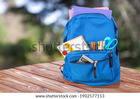 Classic school backpack with colorful school supplies and books on desk. Royalty-Free Stock Photo #1902577153