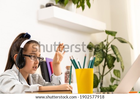 Child online. A little girl uses a laptop video chat to communicate learning while sitting at home.