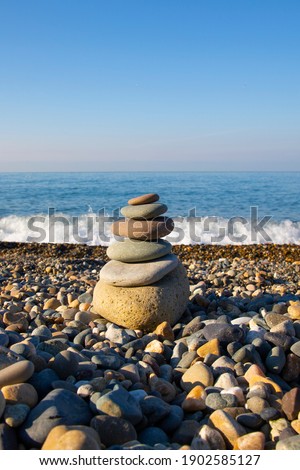 the concept of balance and harmony. stones on the beach in nature. Pyramid of stones on a beach of pebbles, in the background a blurred background of the sea, dawn