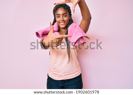 Young african american woman with braids wearing sportswear and towel smiling making frame with hands and fingers with happy face. creativity and photography concept. 