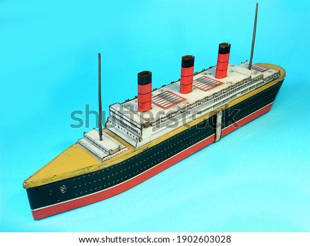A vintage litho printed Crawford's biscuit tin toy ocean liner the Berengaria on a plain blue background. Royalty-Free Stock Photo #1902603028