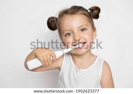 Perfect removing of the plaque with a modern toothbrushPretty little girl cleaning teeth with electric sonic toothbrush.