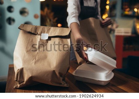woman waitress preparing take away food in restaurant Royalty-Free Stock Photo #1902624934