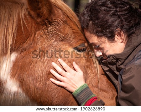 Close up of female in brown jacket forming bond with a piebald pony. Royalty-Free Stock Photo #1902626890