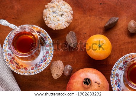 Top view of of traditional turkish tea with cookies , fruits and nuts on red wood table.