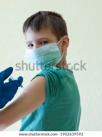 Vaccination concept. Doctor vaccinating cute toddler boy. Yellow background.COVID-19 vaccine Concept of of corona virus treatment, injection, shot and clinical trial during pandemic.