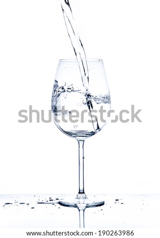 Glass with the stream of dinking water on white background