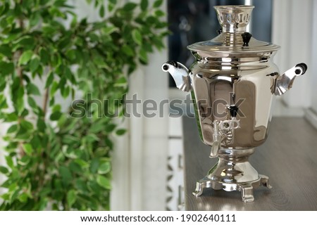 Metal samovar on wooden countertop in kitchen, space for text. Russian tea culture