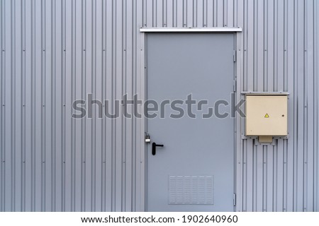 Grey transformer box.Locked electric metal door with a sign of attention on the grey wall of the transformer substation.