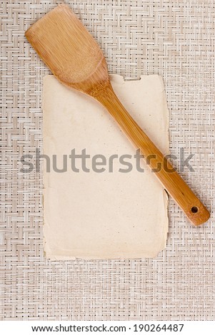 Kitchen wooden spoon and an old sheet of paper for text.
