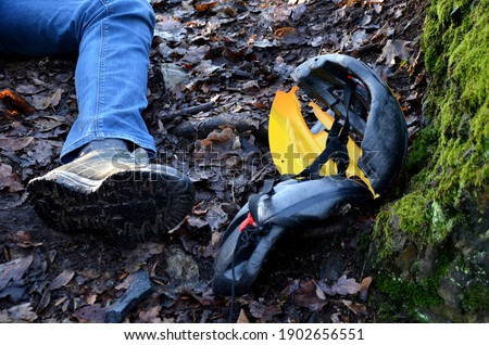 a young man in jeans went down into the woods and smashed his head in a protective helmet. the helmet lies nearby. lie hand and foot without a picture of life. who calls for help