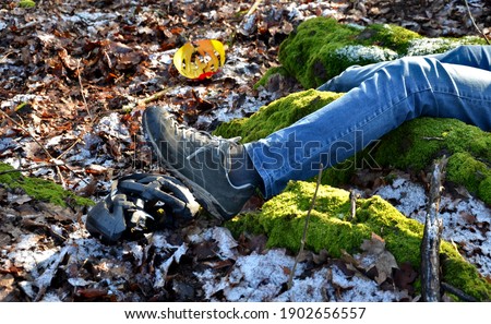 a young man in jeans went down into the woods and smashed his head in a protective helmet. the helmet lies nearby. lie hand and foot without a picture of life. who calls for help