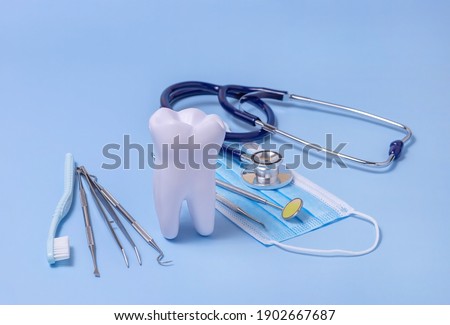 a model of a tooth, dental equipment and a toothbrush on a blue background. concept of oral hygiene