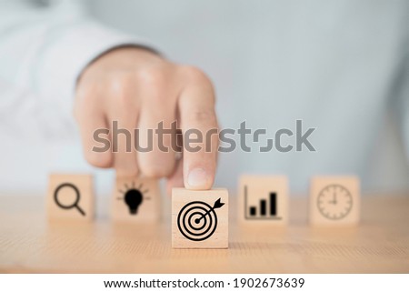 Businessman pushing target dartboard icon in front of others icons to setup business objectives.