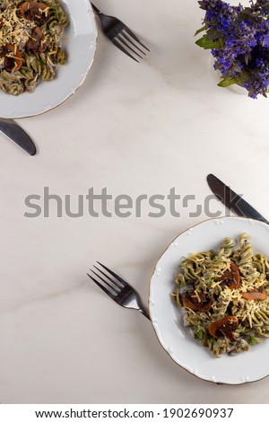Healthy organic spinach pasta with mushroom and cheese served on a white plate. 