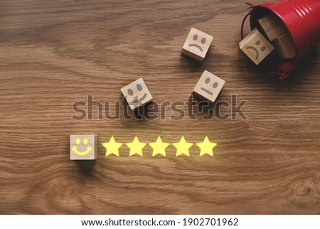 Top view of a fallen red bucket fill with icon of face expression of rating on wooden cube. Customer experience concept.