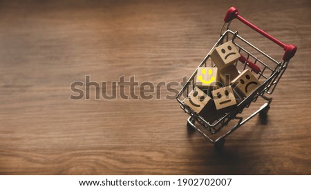 Selective focus of shopping cart and icon of face expression of rating on wooden background with copy space. Customer experience concept.