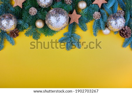 Spruce branch, cones and vintage toys decoration on christmas or new year on yellow background.