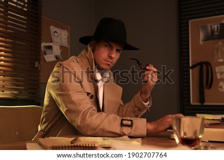 Old fashioned detective with smoking pipe using typewriter at table in office