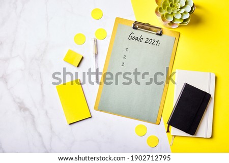 Desktop with clipboard with Goals List mockup and office supplies. Home office, planning goal setting concept. Flatlay, top view