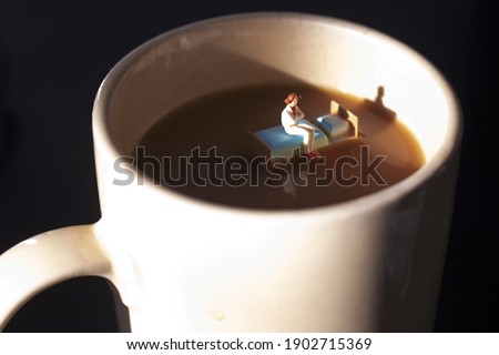 Miniature woman on a bed in a cup of coffee. Waking up with caffeine to start day. Time to start your morning with a hot cup of java. Coffee is a big part of our day.  Insomnia or exhaustion concept.  Royalty-Free Stock Photo #1902715369