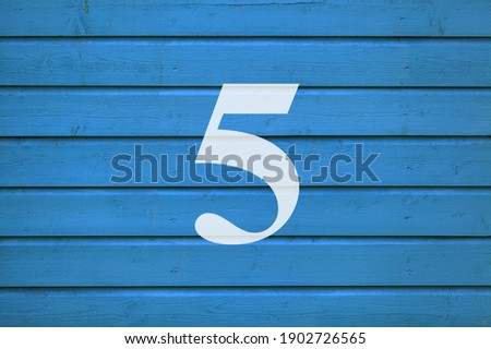Number five on an old blue color wooden door